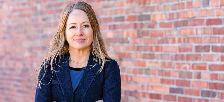 Elizabeth Hausler standing in front of a brick wall