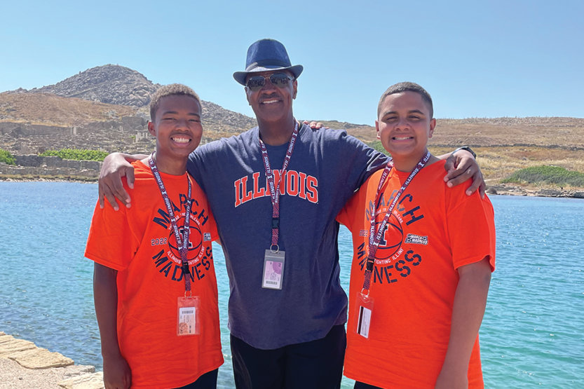 Bryan Terry poses with is son Delos and nephew Xavier on a sunny, rocky, arid shoreline.