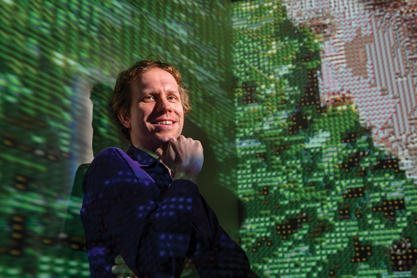 Professor Wade Fagen-Ulmschneider standing against a projected, green digital wall.
