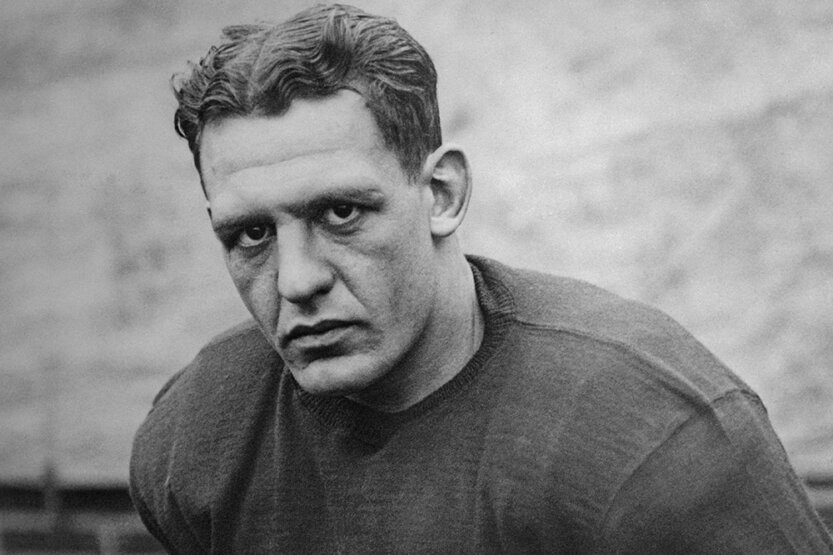 Red Grange poses holding a football