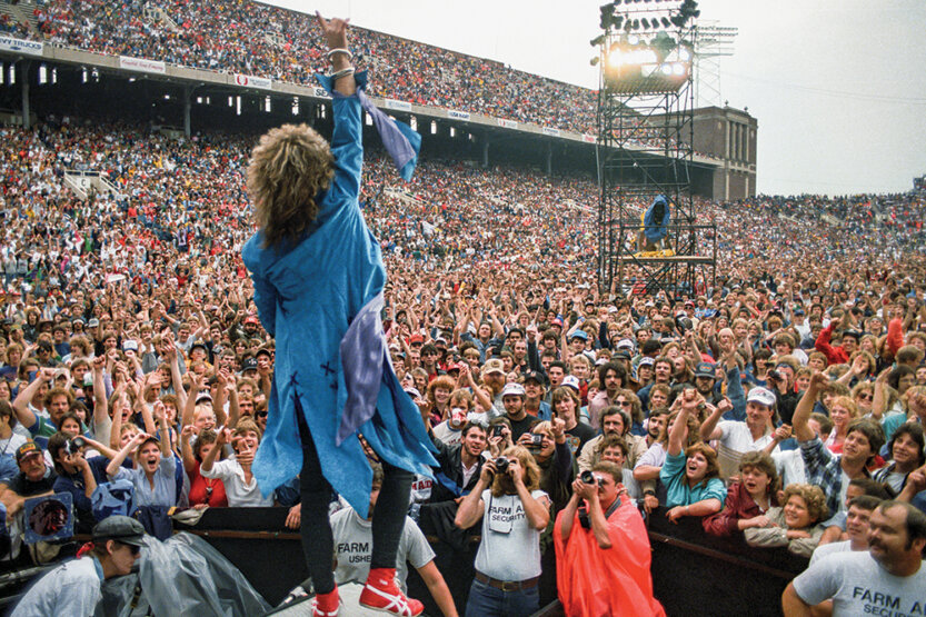 Jon Bon Jovi on stage of packed outdoor stadium