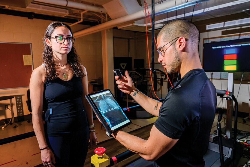 Woman wearing smart shirt while man reviews incoming data on a tablet
