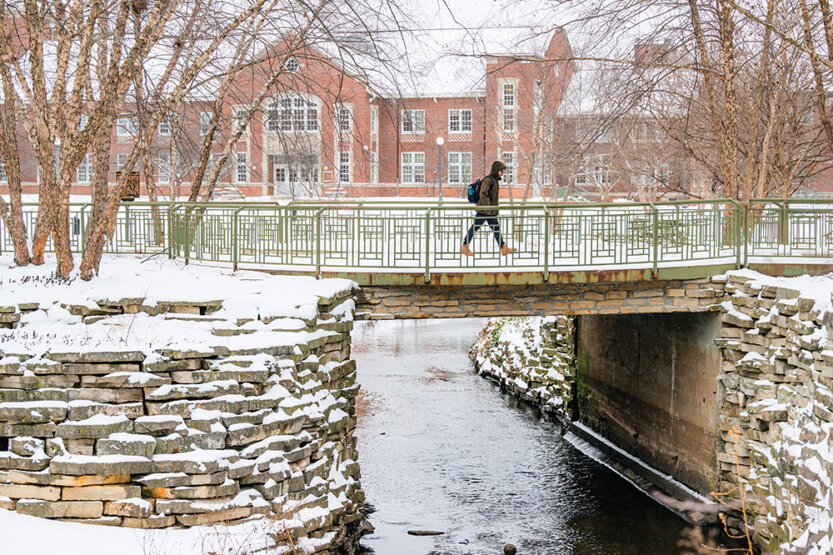 Person crossing a snowy Boneyard creek bridge