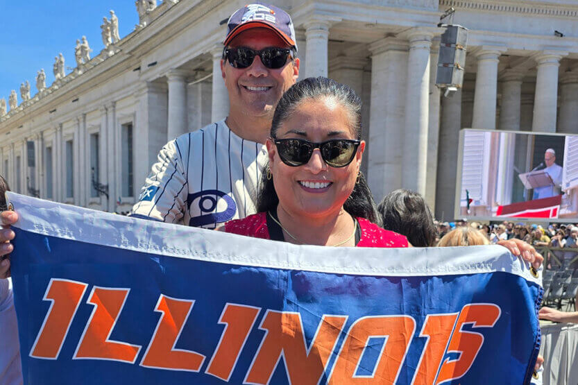 Adam and Grace Delgado holding Illini flag at the Vatican