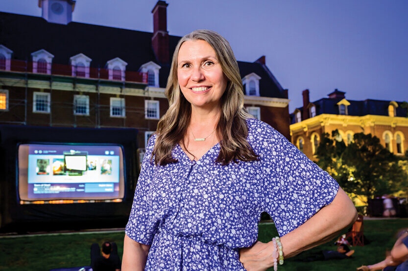 Becki Salzman in front of large screen on the quad