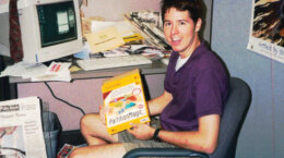 Brian Costello seated in an office holding a computer software box
