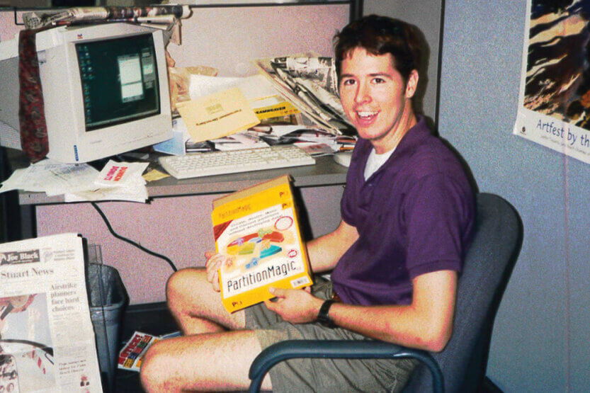 Brian Costello seated in an office holding a computer software box