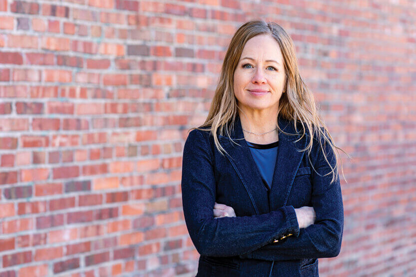 Elizabeth Hausler standing in front of a brick wall