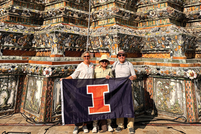 Individuals holding a university flag in front of an ornate temple