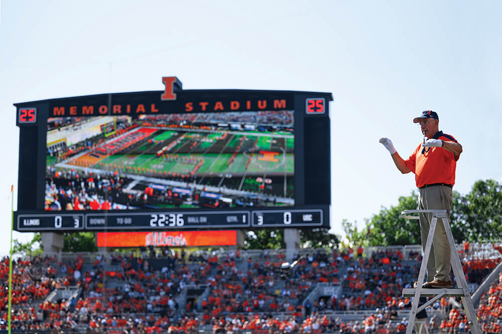 Gary Smith on a ladder conducting a marching band